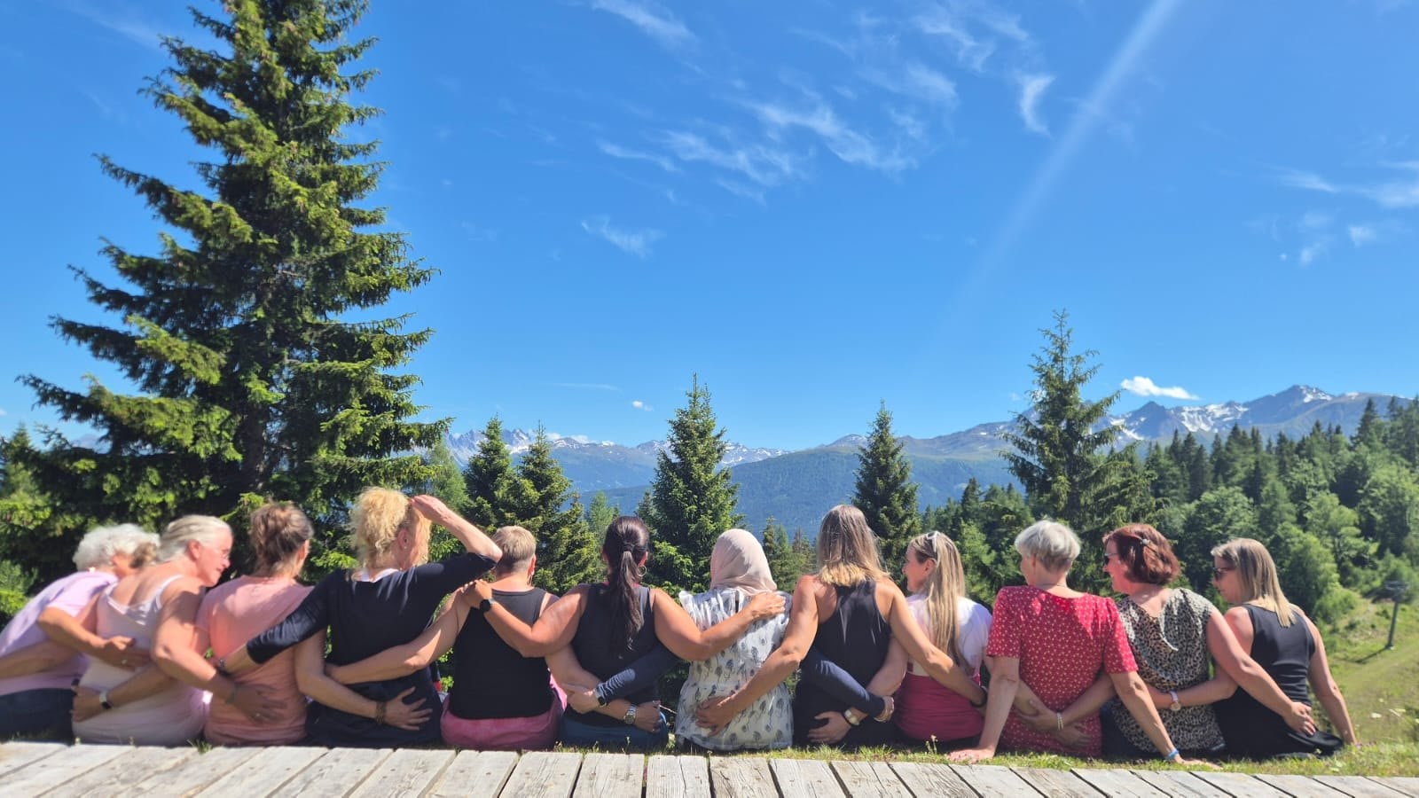 Die Gruppe eines vergangenen FreyMuT Retreats sitzt Arm in Arm und blickt in die Weite